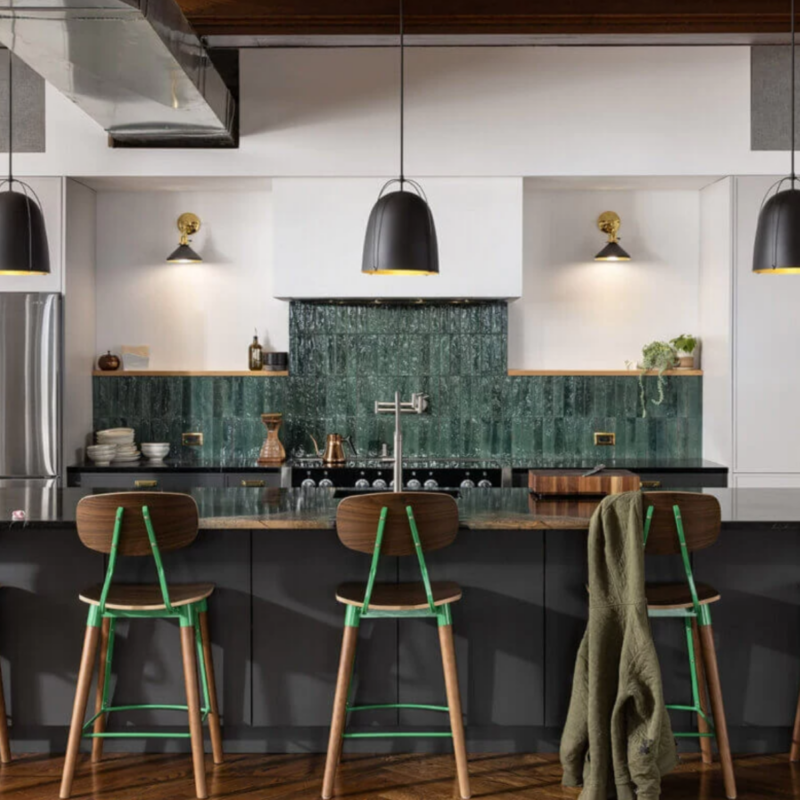 A kitchen with a green backsplash and a black pendant light are highlights of this JC Huffman Cabinetry.