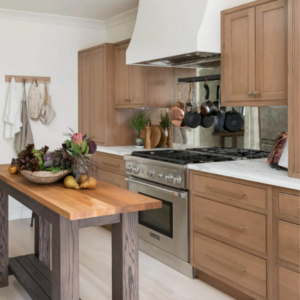 A kitchen with wood cabinets, a white hood and a simple wood island workstation highlight this remodel by JC Huffman Cabinetry.