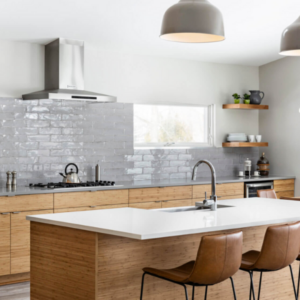 Gray subway tiles on a backsplash, light wood cabinets and two brown leather barstools highlight this JC Huffman kitchen remodel.