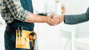 man with toolbelt shakes hand of a female homeowner.