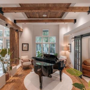 Reclaimed barnwood used on ceiling beams above a black piano.
