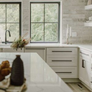 A white kitchen with gray stone wall.