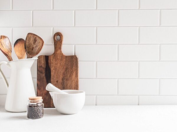 White subway kitchen backsplash tile with wood cutting boards and utensils on a bright white countertop.