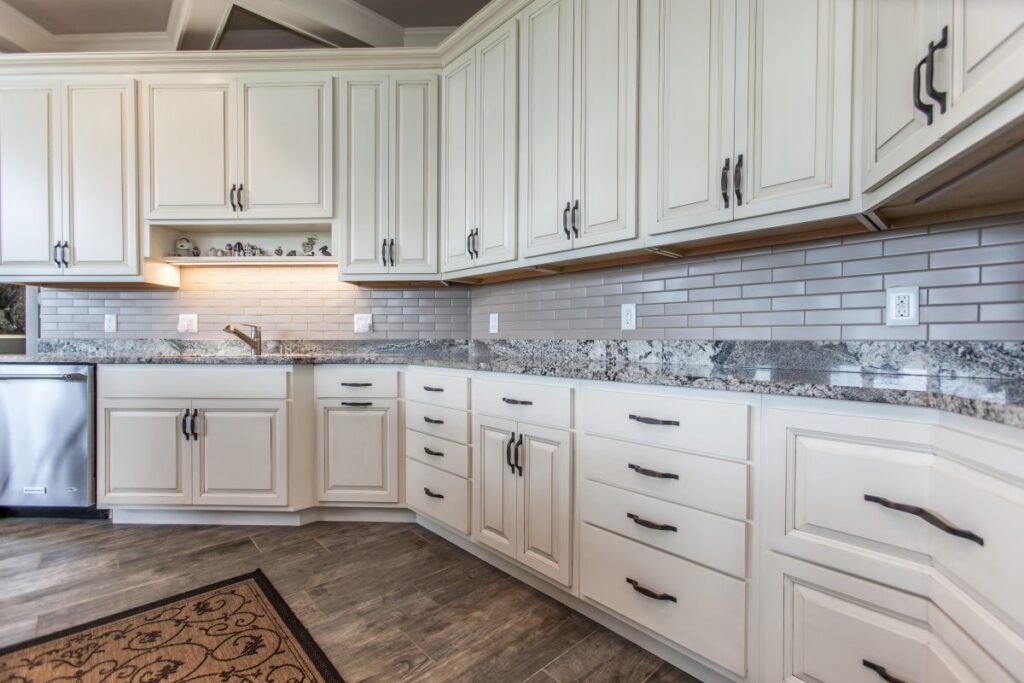 A bright and welcoming kitchen remodel in Mt Pleasant IA featuring custom antique white cabinets and elegant granite countertops that beautifully reflect natural light.