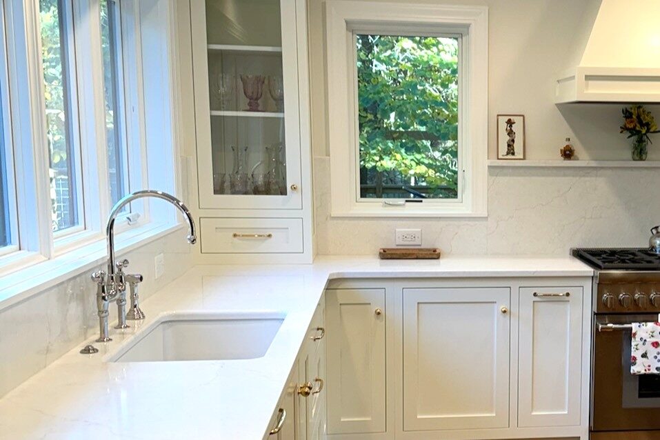 Benjamin Moore Simply White kitchen cabinets with white quartz countertops and brass hardware in a Fairfield, Iowa, home.
