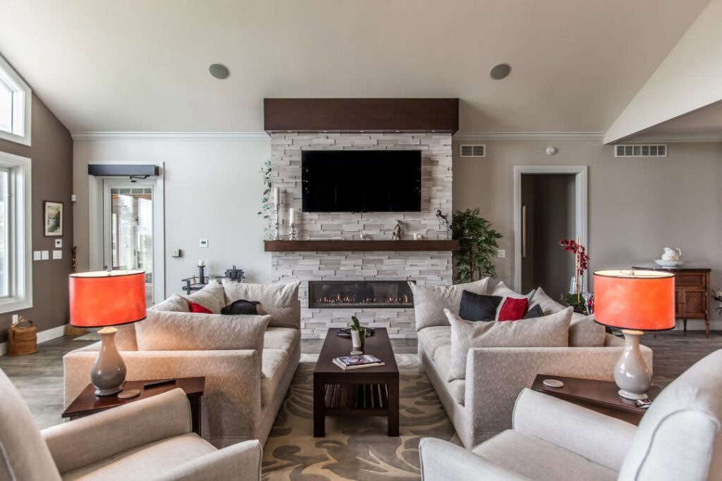 Modern linear gas fireplace in a stacked-stone living room feature wall with a wood mantel and seating area.